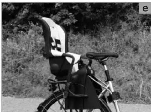 Black-and-white photo of a bicycle rear seat with black and white seats, parked outdoors near trees (no visible text or symbols)