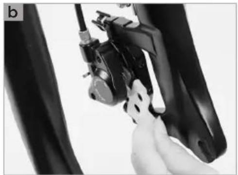 Close-up of a hand adjusting a bicycle brake caliper on a vehicle chassis (no visible text or symbols)