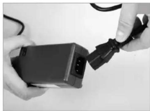 Close-up of hands holding a black electronic device with cable, no visible text or symbols