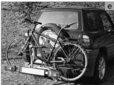 Black-and-white photo of a car with bicycles mounted on a vehicle chassis, parked outdoors (no visible text or symbols)