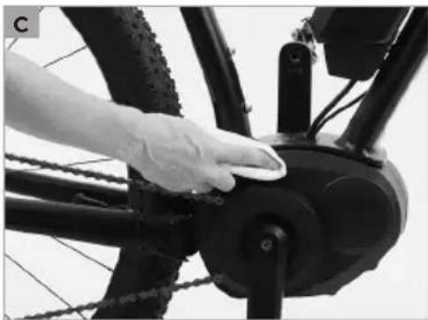 Close-up of a hand cleaning a bicycle wheel with chains and a circular component (no text or symbols visible)