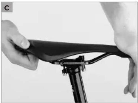 Close-up of hands assembling a black bicycle seat frame on a tripod (no text or symbols visible)