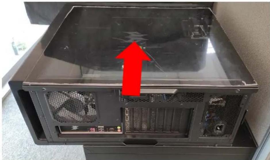 Interior view of a computer tower case with visible fan and drive slots, marked by a red upward arrow (no text or symbols)
