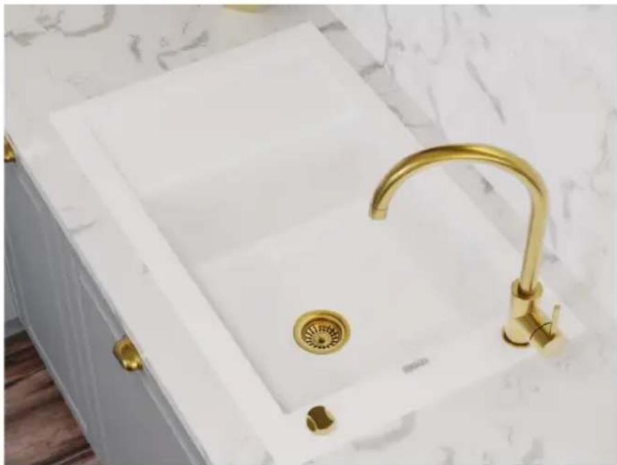 Modern white kitchen sink with gold faucet and circular drain, placed on a patterned surface (no text or symbols visible)