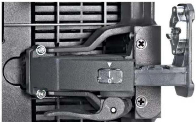 Close-up of a mechanical component with mounting holes and a central switch (no visible text or symbols)