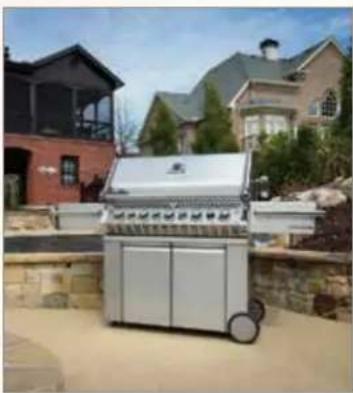 Exterior view of a modern electric grill with a groggy and wheels, surrounded by residential houses (no signage or text visible)