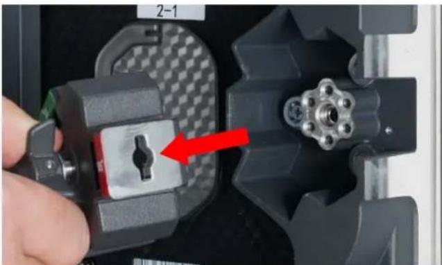 Close-up of a hand inserting a mechanical component into a device housing (no visible text or symbols)