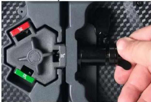 Close-up of a hand holding a black mechanical component with visible ports and a 90° angle indicator (no text or symbols on the component itself)