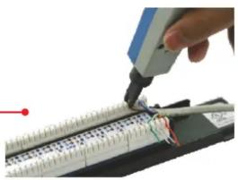 Close-up of a hand using a pen to cut or mark a cylindrical electronic component with wires (no visible text or symbols)