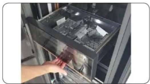 Hand placing a small object into a glass appliance. No visible text or symbols.