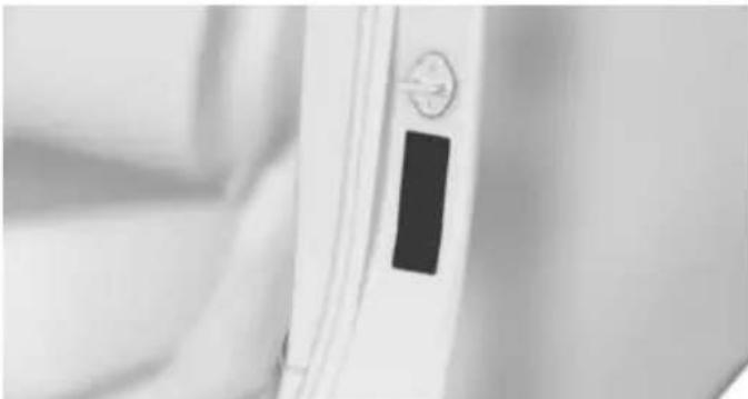 Close-up of a white door panel with a black rectangular object on the side (no visible text or symbols)