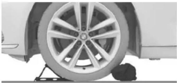 Close-up of a car wheel mounted on a lift, showing tire and wheel rim (no text or symbols visible)