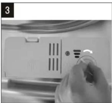 Close-up of a hand holding a small circular object next to a white appliance with ventilation slots and a scroll (no visible text or symbols)