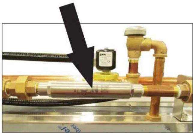 Close-up of industrial pipe fittings and valves with a black arrow pointing to a component (no visible text or symbols)