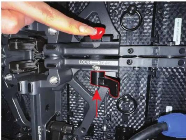 Close-up of a hand adjusting a black mechanical component with a red knob, showing no visible text or symbols.