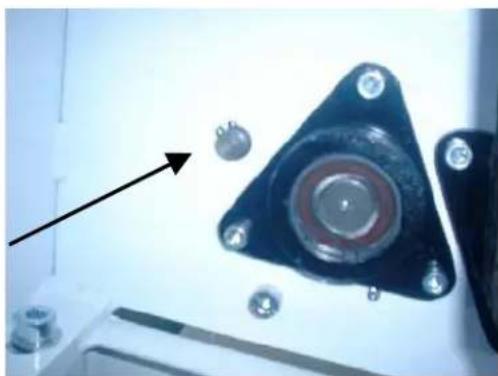 Close-up of a black triangular mechanical component with multiple screws and a central circular ring, no visible text or symbols.