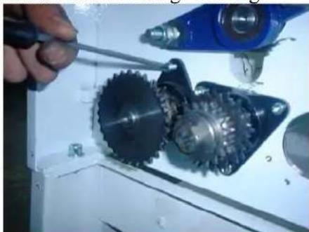 Close-up of mechanical gears and a blue tool on a white industrial machine (no visible text or symbols)