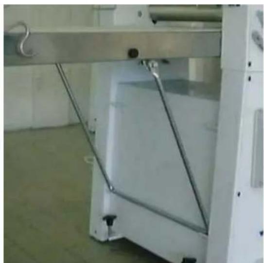 Interior view of a white industrial machine with metal frame and handle, no visible text or symbols