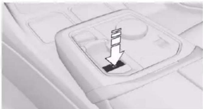 Close-up of a car interior panel with a black button and a white arrow pointing downward (no text or symbols)