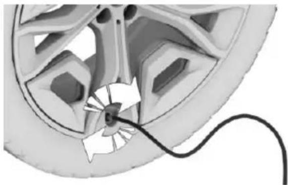 Close-up of a car wheel with a cable inserted, showing internal components and a white arrow indicating motion (no text or symbols)