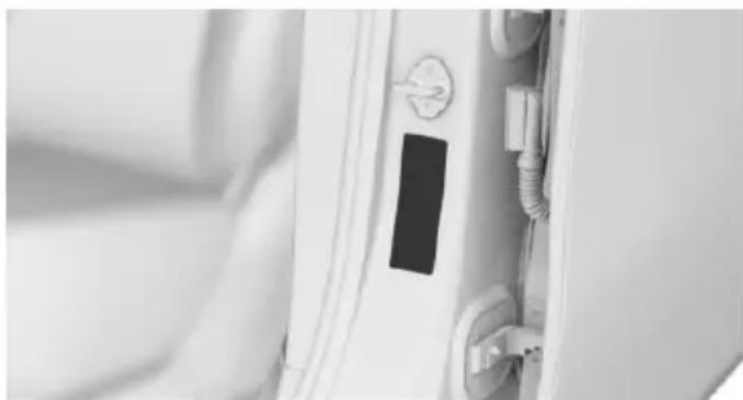 Close-up of a white door with a black rectangular component inserted, showing wiring and a switch (no text or symbols visible)