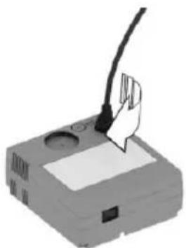 Illustration of a handheld electronic device with a cable and a paper clip inserted (no text or symbols visible)