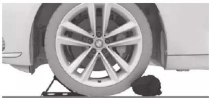 Close-up of a car wheel mounted on a lift, showing tire and wheel rim (no text or symbols visible)