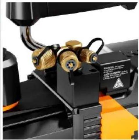 Close-up of a 3D printer with brass fittings and orange base, no visible text or symbols
