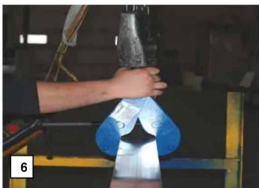 Person handling a metallic object in a factory setting (no visible text or symbols)