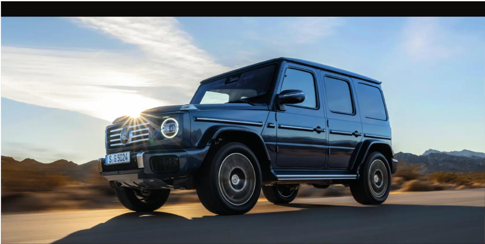 Mobil Mercedes-Benz G-Class hitam melaju di jalan gurun saat matahari terbenam, dengan latar belakang pegunungan (tanpa teks atau simbol yang terlihat)