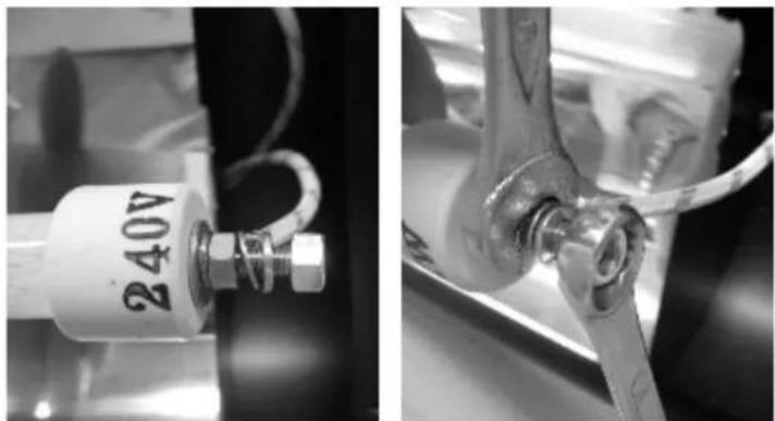 Close-up of two mechanical components: a cylindrical component labeled '240V' and a metal clamp with a tool inserted (no visible text or symbols)