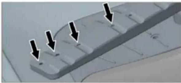 Close-up of a mechanical component with four downward-pointing arrows indicating features (no text or symbols present)