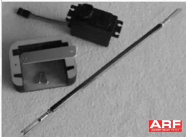 Close-up of electronic components including a metallic rod, a small mechanical component, and a control module (no visible text or symbols)