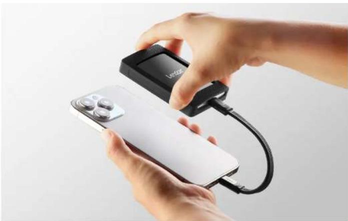 Close-up of hands holding a white remote control device connected to a black electronic device labeled 'Lexiage', with no visible text or symbols on the device itself.