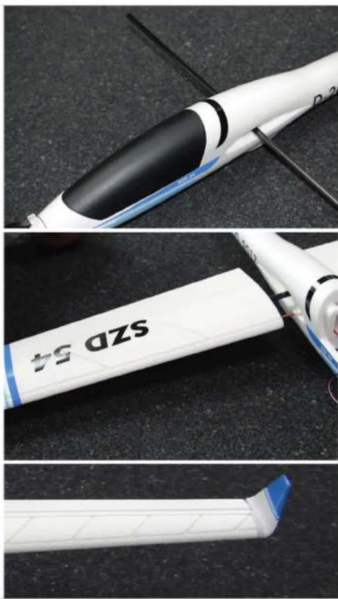 Close-up of a white and black model turbine blade with 'SZD 54' branding, shown from three different angles (top, front, side) against a dark textured background.