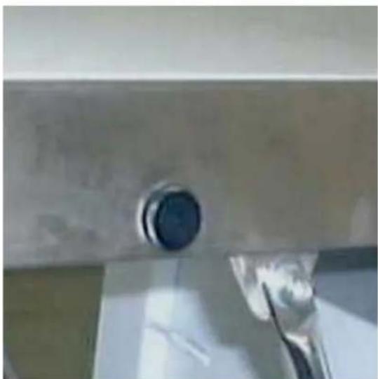 Close-up of a metallic screw head with a circular head and a small tool inserted (no visible text or symbols)