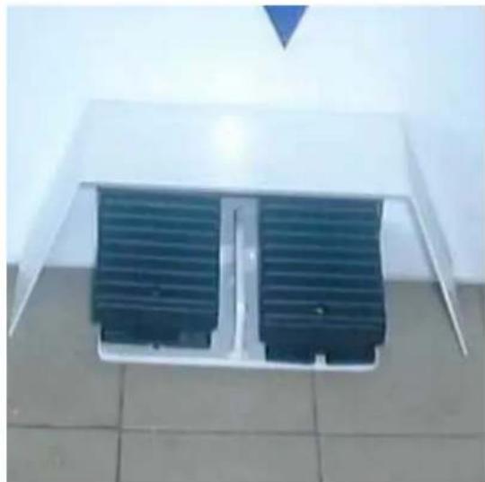Exterior view of a white roof-mounted air vent with two blue heat sinks mounted on tiled floor (no text or symbols visible)