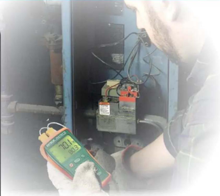 Person inspecting electrical equipment with a digital multimeter (no visible text or symbols)