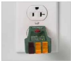 Close-up of a green electrical socket with orange buttons and a white power outlet (no visible text or symbols)