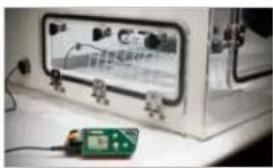 Laboratory setup with a large digital display and a green control panel (no visible text or symbols)