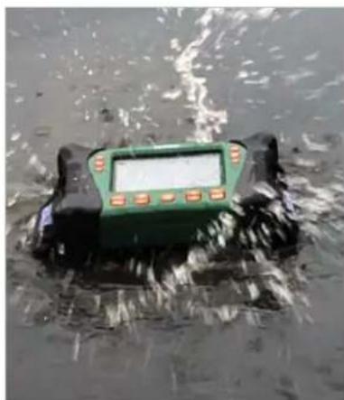 Green handheld device partially submerged in water, no visible text or symbols