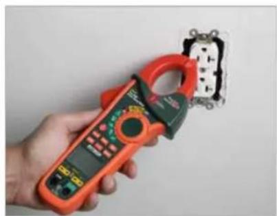 Hand holding an orange multimeter with a close-up of its circuit board (no visible text or symbols)