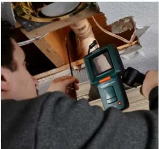 Person using a handheld device to inspect or repair a mechanical component (no visible text or symbols)