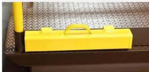 Close-up of a yellow plastic component mounted on a metal perforated surface (no text or symbols visible)