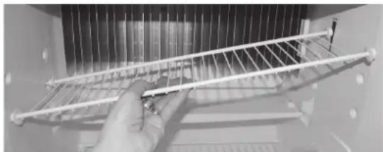Close-up of a hand holding a metal rack with grid lines, no visible text or symbols