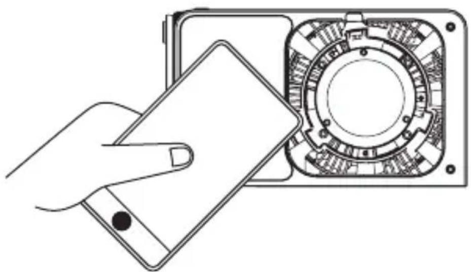 Line drawing of a hand holding a smartphone next to a circular mechanical component (no text or symbols)