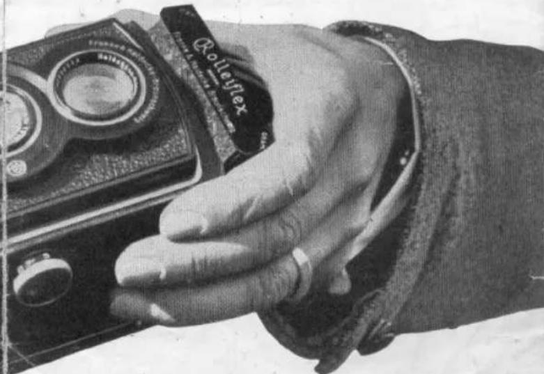 Close-up of a hand holding a vintage camera with a label reading 'Rouleflex' (no other visible text or symbols)