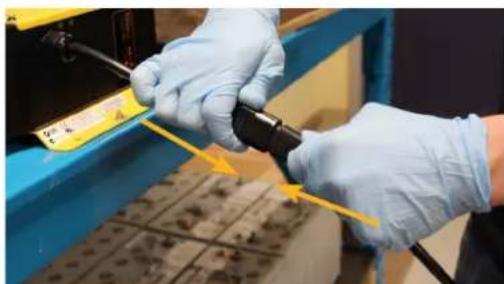 Close-up of gloved hands performing maintenance on a blue industrial machine component (no visible text or symbols)