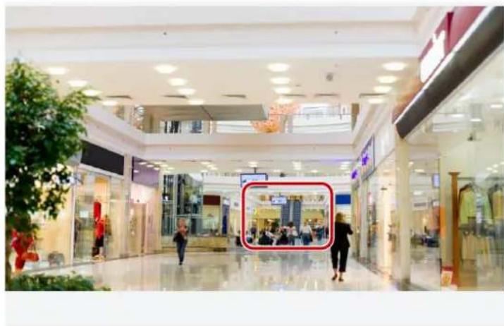 Interior view of a modern shopping mall with visible store windows and shoppers (no signage or readable text)