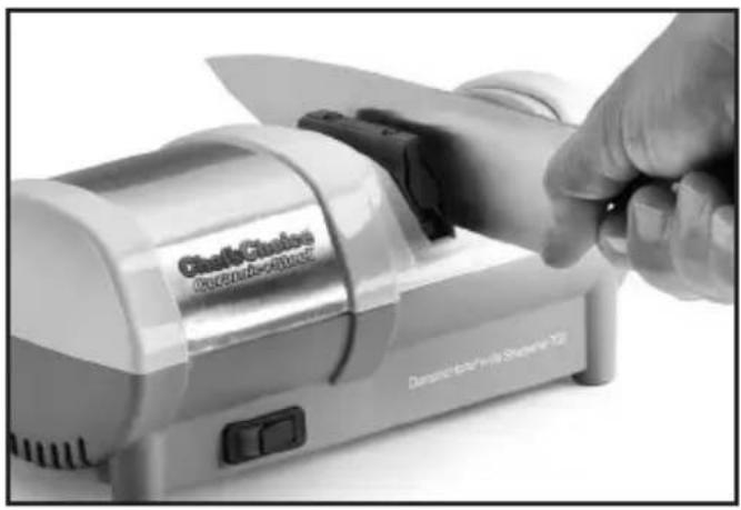 Close-up of a hand using a Clutch Cinics electric shaver on a flat-screen TV (no visible text or symbols on the device itself)